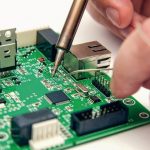 Male_hands_solder_components_onto_a_printed_circuit_board_using_copper_and_a_soldering_iron._Electronics_repair._Selective_focus._