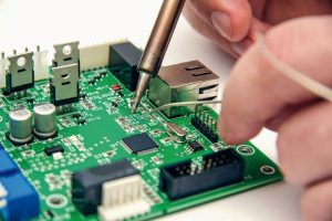 Male_hands_solder_components_onto_a_printed_circuit_board_using_copper_and_a_soldering_iron._Electronics_repair._Selective_focus._